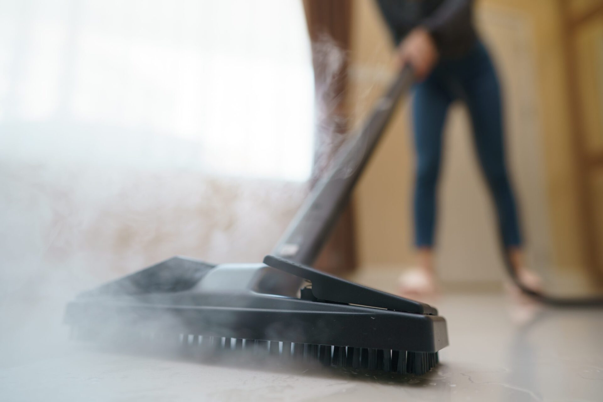 Persona netejant el terra amb una fregona de vapor